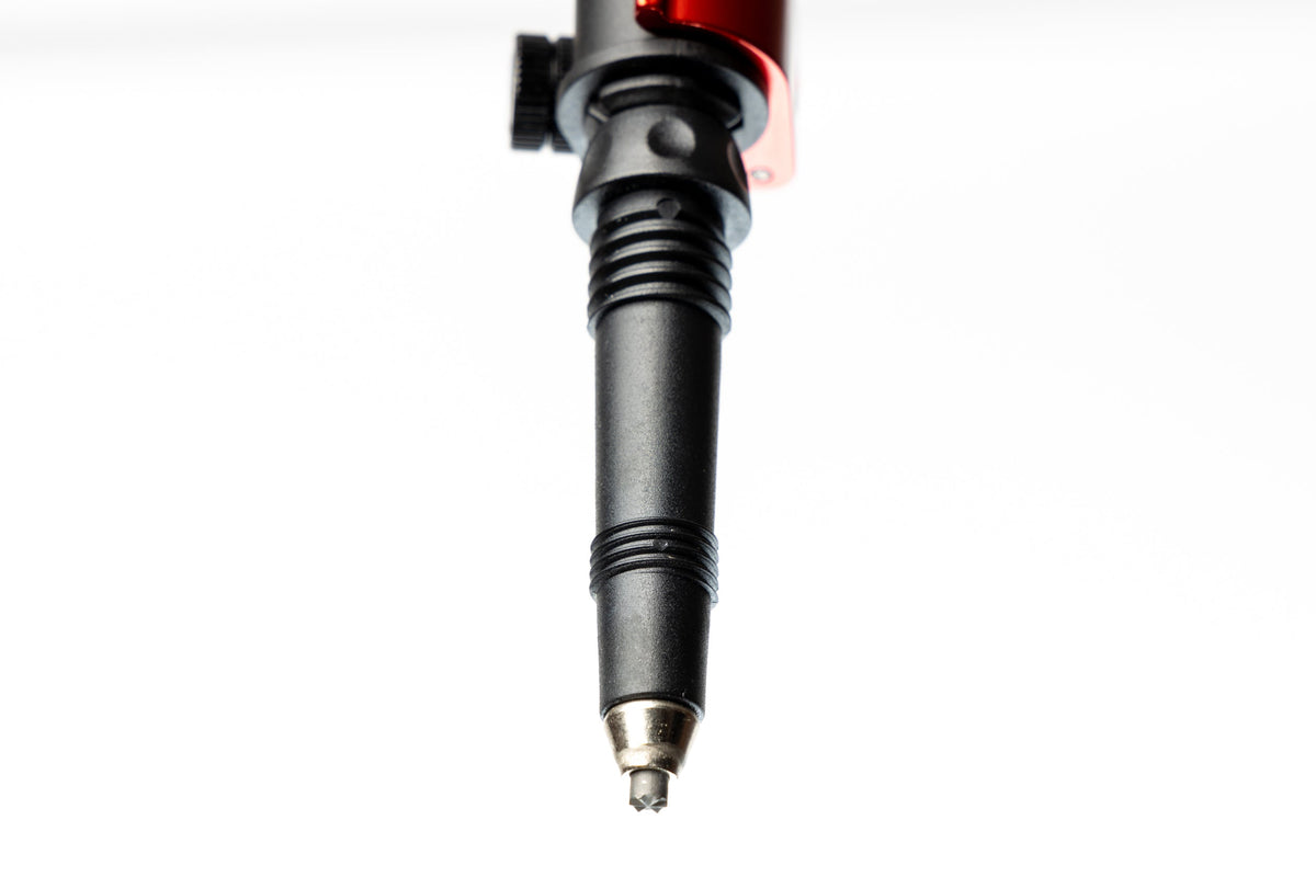 Close-up view of a black trekking pole lower section with a carbide tip and a red adjustment knob.